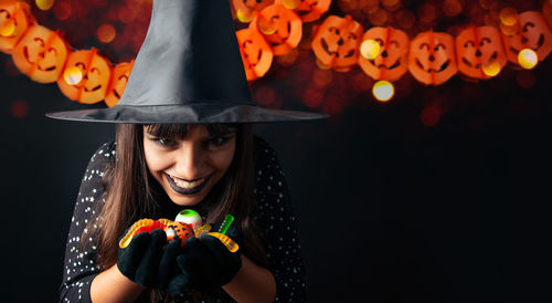 Portrait of young woman wearing hat against black background