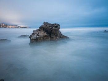 Scenic view of rocks in sea against sky