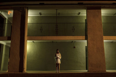 Full length of woman with candle standing in corridor at night