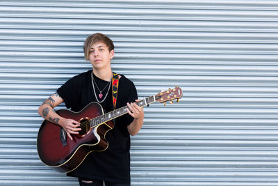 Full length of a man playing guitar against wall