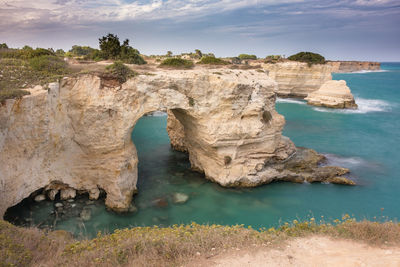 Rock formations on sea shore against sky