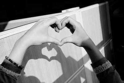 Close-up of hands making heart shape on wooden wall