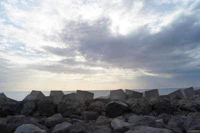 Rocks by sea against sky during sunset
