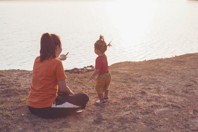 Woman gesturing while showing lake to daughter