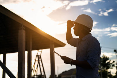 Side view of engineer using digital tablet against sky at sunset