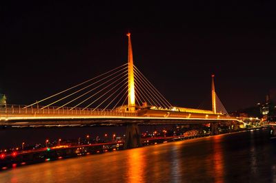 Illuminated bridge over river at night