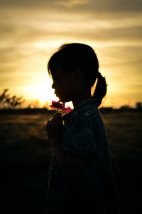 Side view of silhouette girl standing against sky during sunset