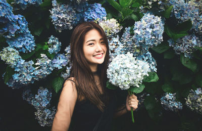 Portrait of a smiling young woman against plants