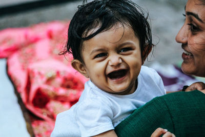 Close-up of mother carrying cheerful toddler daughter