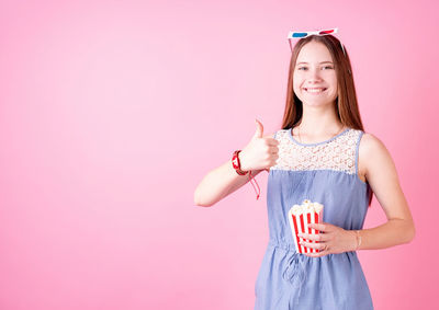 Portrait of a smiling young woman against pink background