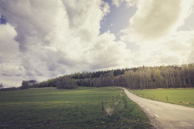 Road amidst field against sky