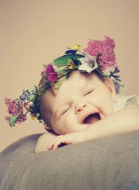 Close-up of cute toddler wearing flower wreath lying on bed at home