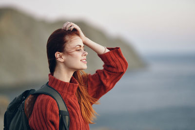 Young woman looking away while standing outdoors