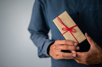 Midsection of man holding paper against white background