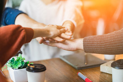 Cropped image of people stacking hands at cafe