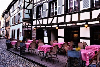 Empty chairs and tables at sidewalk cafe in city