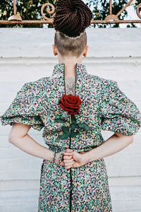 Back view of woman with tattoo ukrainian trident symbol holds a red rose in her hands. ukrainian