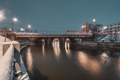 Bridge over river in city against sky at night