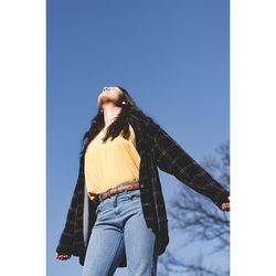 Low angle view of woman standing against clear blue sky