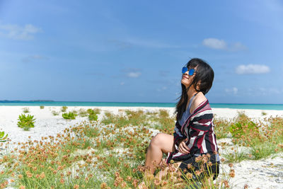 Young woman at beach against sky