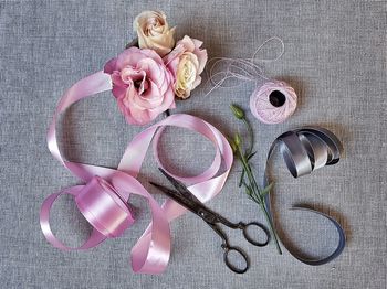 Directly above shot of scissors with roses and ribbon on table