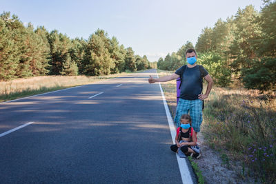 Man standing on road against trees