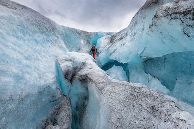 Rear view of man standing on glacier against sky