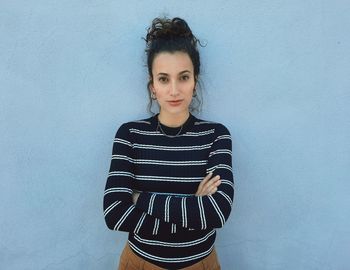 Portrait of beautiful young woman standing against wall