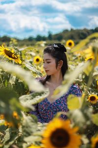 Portrait of woman with sunflower in field