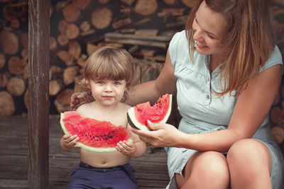 Smiling mother feeding watermelon to son outdoors