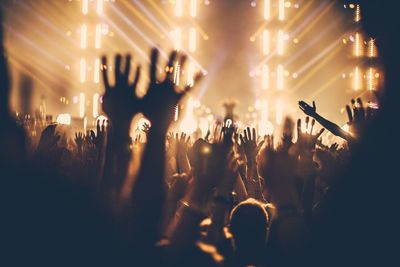 People enjoying music concert with hands raised at night