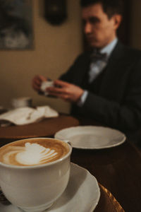 Midsection of businessman holding coffee on table