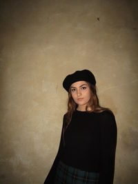Portrait of a young woman standing against wall