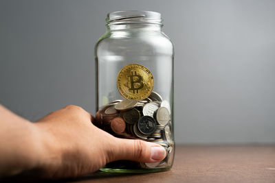 Close-up of hand holding glass jar on table