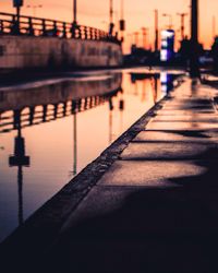 Reflection of illuminated bridge in river during sunset