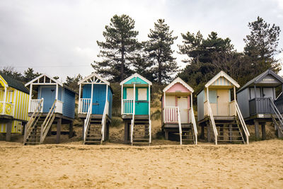 Houses on beach by trees against sky