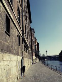 Footpath amidst buildings against clear sky