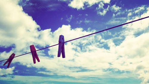 Low angle view of clothespins on clothesline against sky