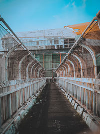 Empty footpath leading towards old building against sky