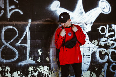 Rear view of man standing against graffiti wall