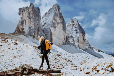 Female hiker balancing on tree trunks against mountain range 