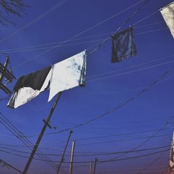 Low angle view of power lines against blue sky