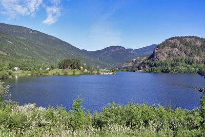 Scenic view of lake and mountains against blue sky