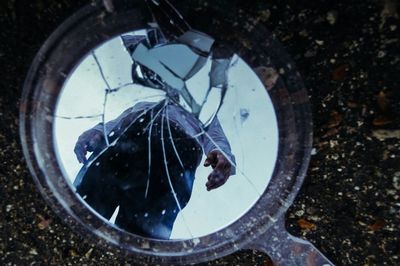 High angle view of man reflecting on broken mirror