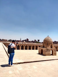 Rear view of man standing against built structures
