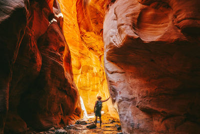 Young man wearing a hat, exploring a slot canyon in kanarra fall, utah