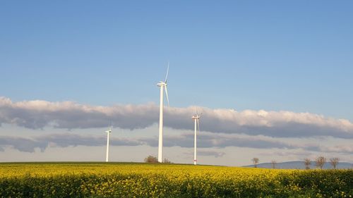 Wind turbines on field against sky