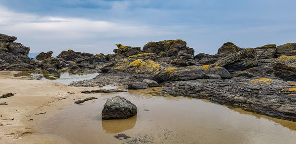 Rock formation on beach against sky