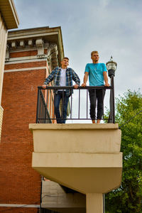 Low angle view of young man standing with teenage boy in balcony