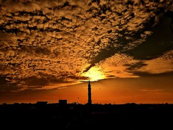 Silhouette of factory against sky during sunset